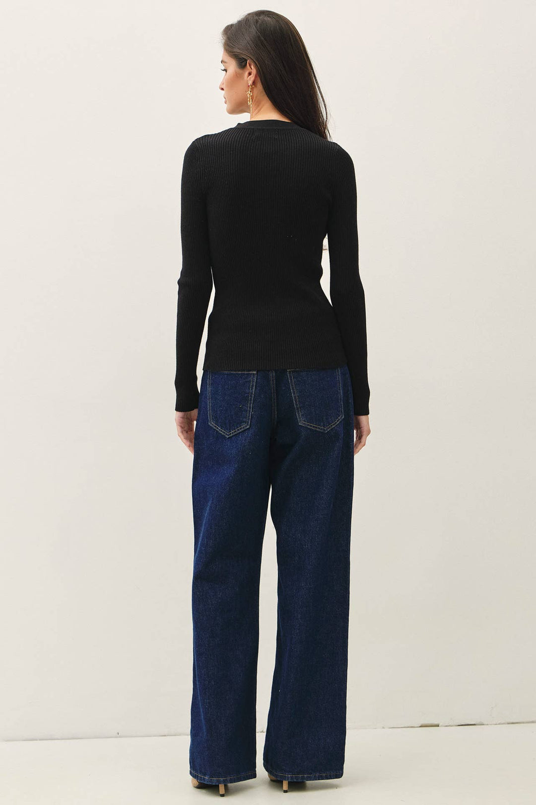 Model wearing a black CAL JUNE slim-fit ribbed cardigan with long sleeves and a crew neck, paired with blue jeans.