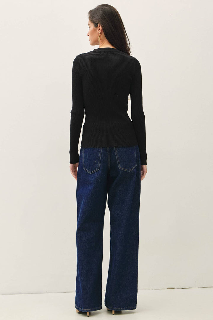 Model wearing a black CAL JUNE slim-fit ribbed cardigan with long sleeves and a crew neck, paired with blue jeans.