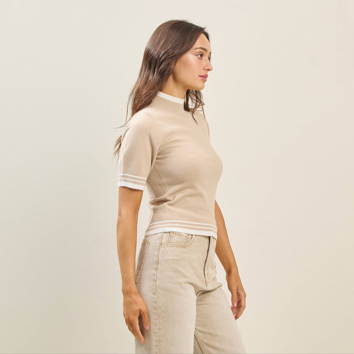 CAL JUNE The Arden Knit Top in beige with white trim on sleeves and hem. Mock neck, short sleeves.