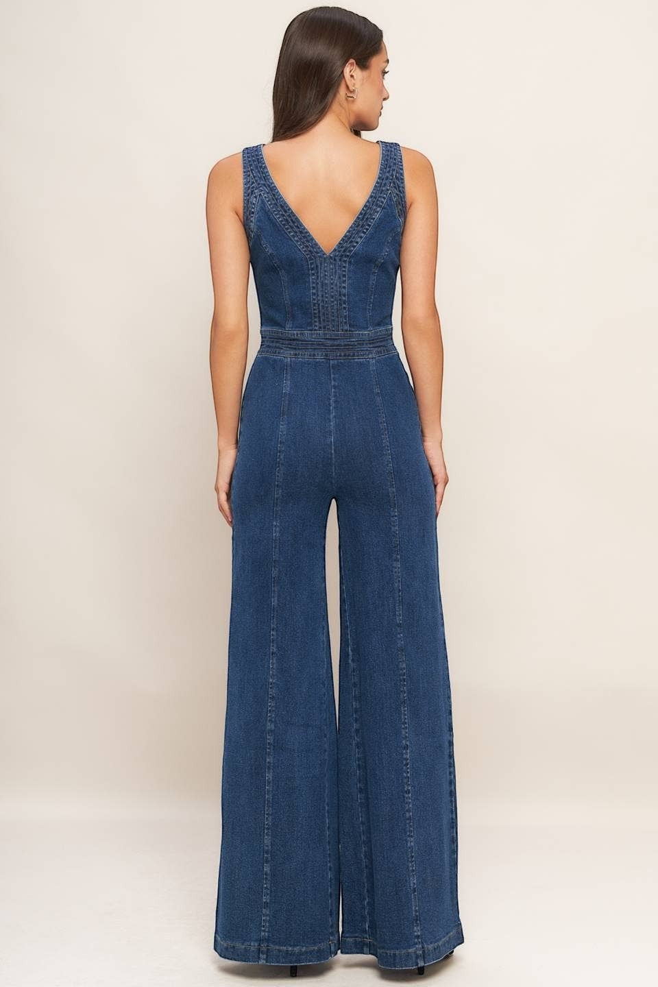 CAL JUNE Aurelia Denim Jumpsuit in medium wash blue with V-neck and wide legs. Model is wearing size Small.