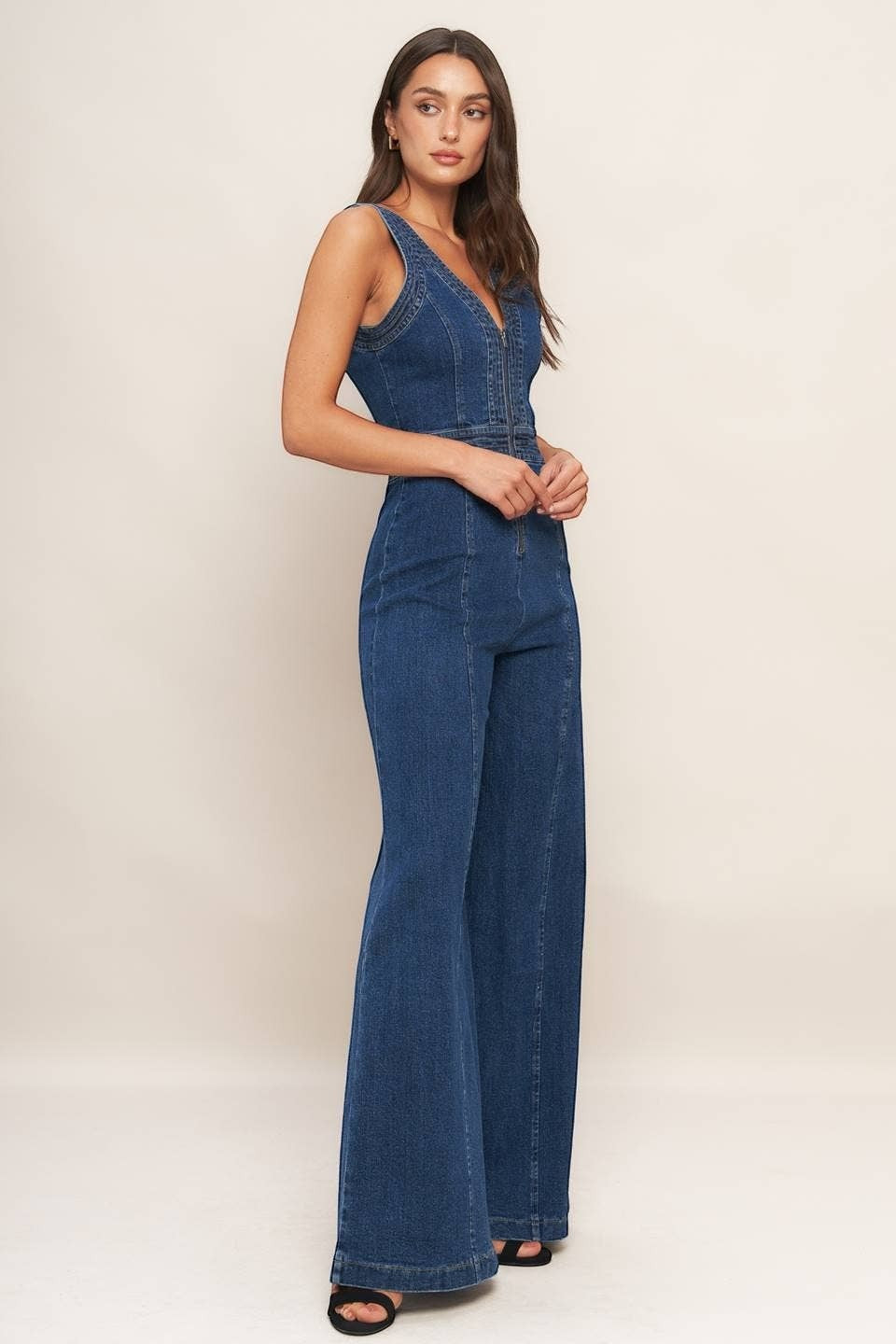 CAL JUNE Aurelia dark wash denim jumpsuit with V-neck, sleeveless design, and flared legs. Model wears size Small.