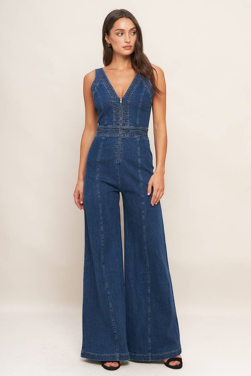 CAL JUNE Aurelia Denim Jumpsuit with V-neck, zipper front, and wide flare legs. Model is wearing size Small.