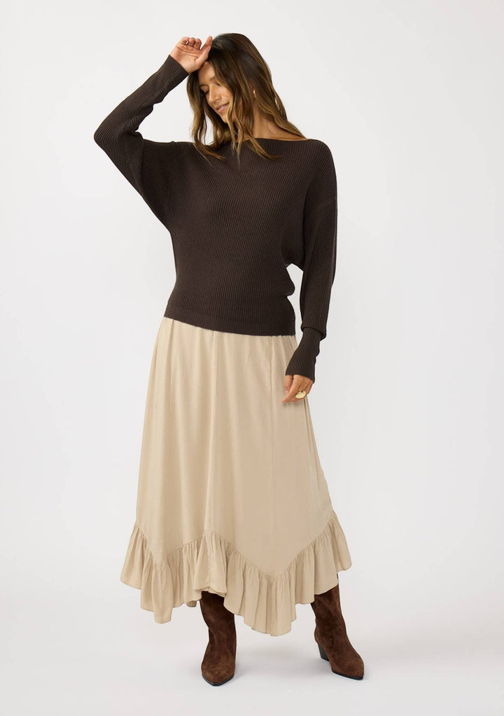 CAL JUNE The Avery Knit Top in dark brown, a ribbed boatneck sweater with dolman sleeves, paired with a beige ruffled midi skirt.