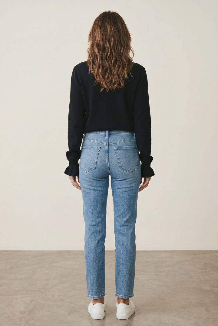 CAL JUNE black knit V-neck top with ruffle cuffs, paired with light wash straight-leg jeans.