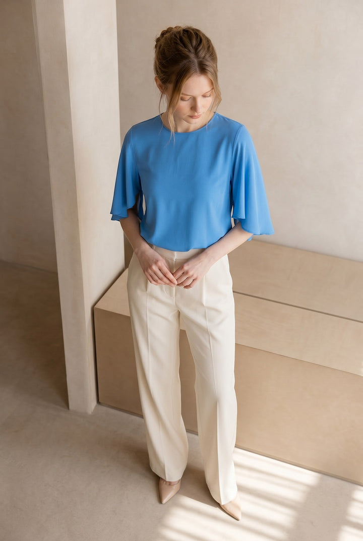 CAL JUNE blue short-sleeve flowy blouse with wide-leg cream trousers. Model wears size Small.