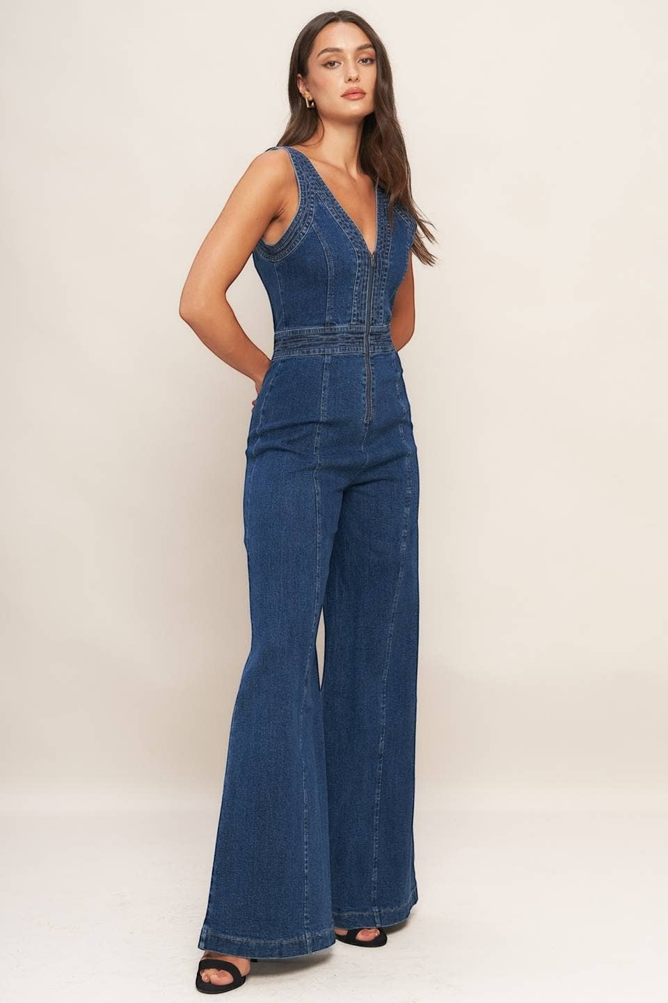 CAL JUNE blue denim flared leg jumpsuit with V-neck and front zipper, worn by a model.