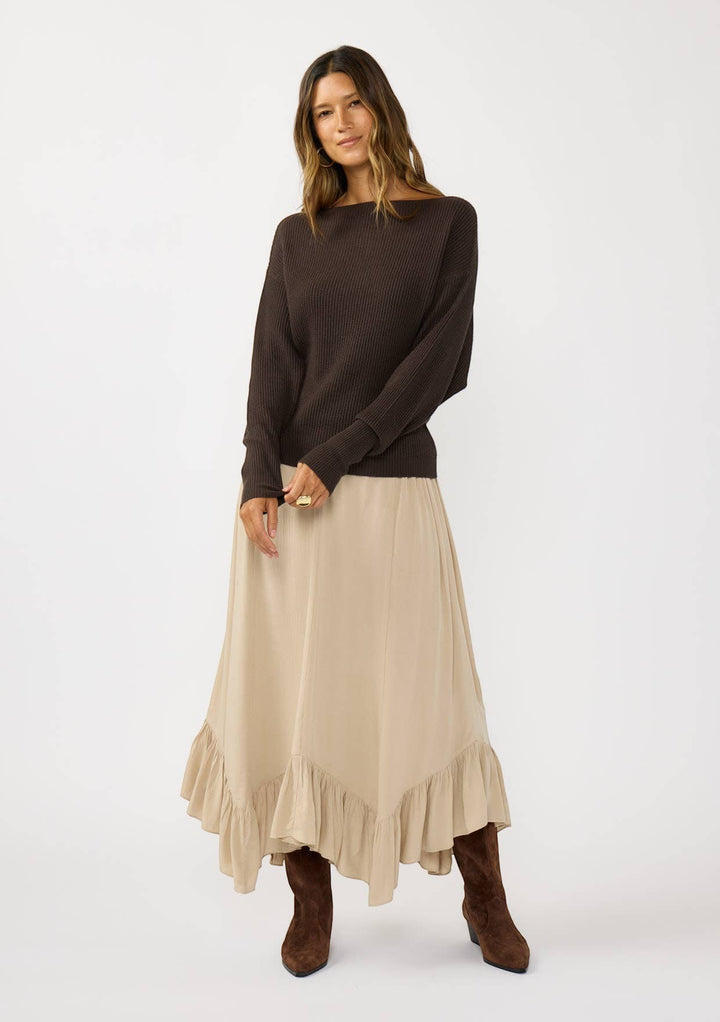 CAL JUNE dark brown ribbed knit boat neck sweater with long sleeves, worn by a model with a beige ruffled skirt.