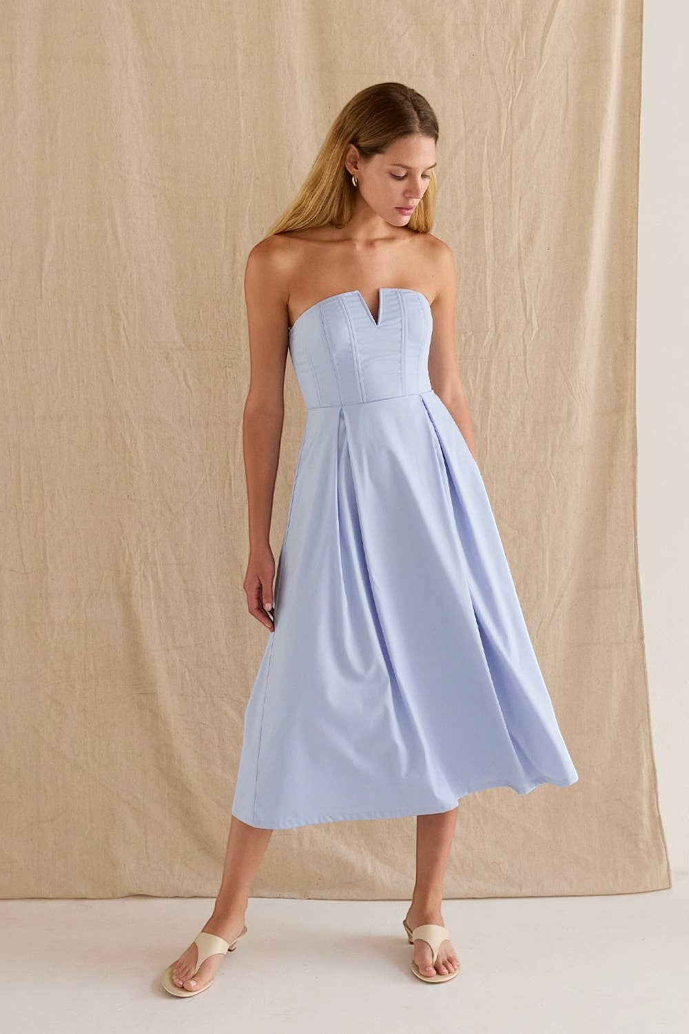 CAL JUNE Elara Strapless Midi Dress in light blue, featuring a sculpted bodice with boning and V-wire neckline, and a pleated skirt.