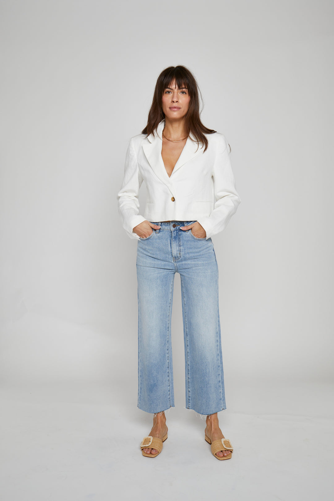 CAL JUNE light indigo worn wash high-rise wide-leg cropped jeans with raw hem on a model.