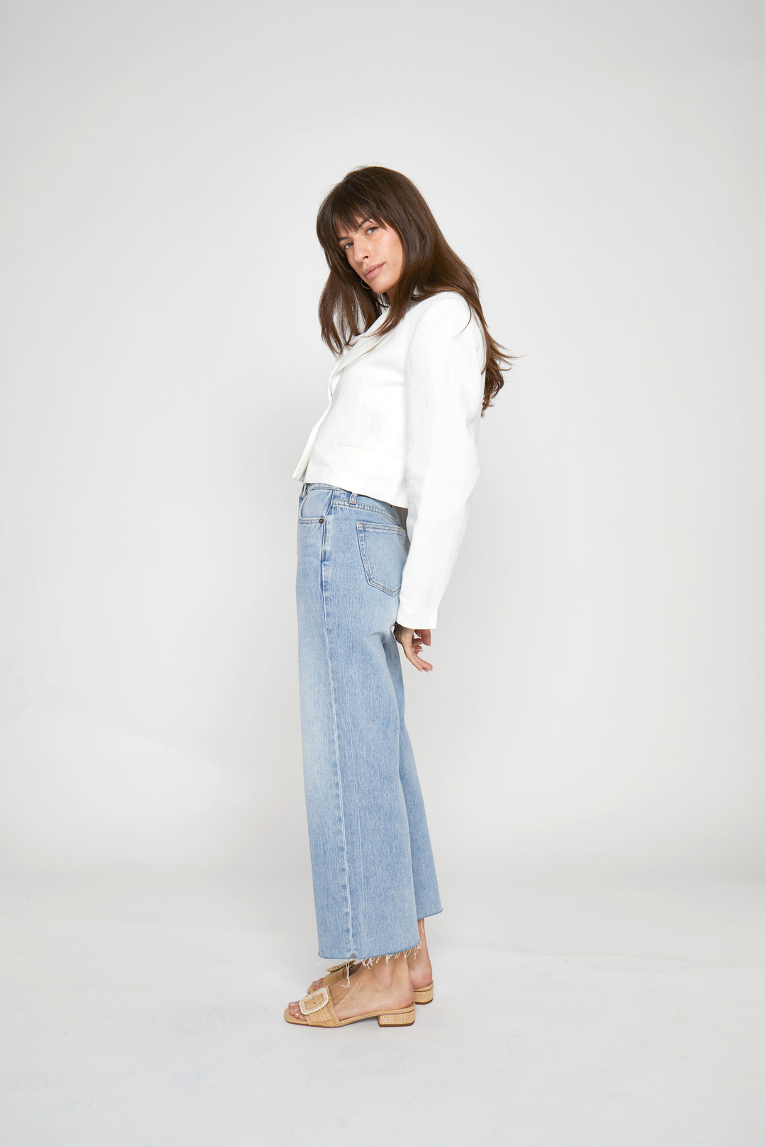 CAL JUNE light indigo worn high-rise wide leg cropped jeans with raw hem on a model.