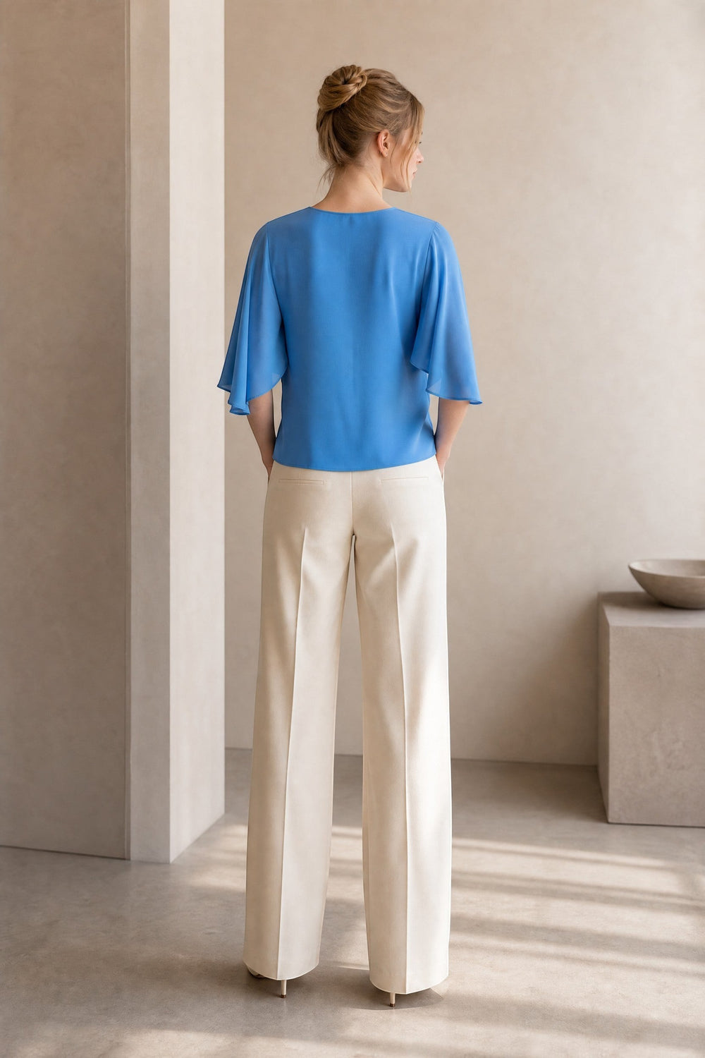CAL JUNE blue flowy sleeve Marais blouse on a woman wearing cream wide-leg pants.