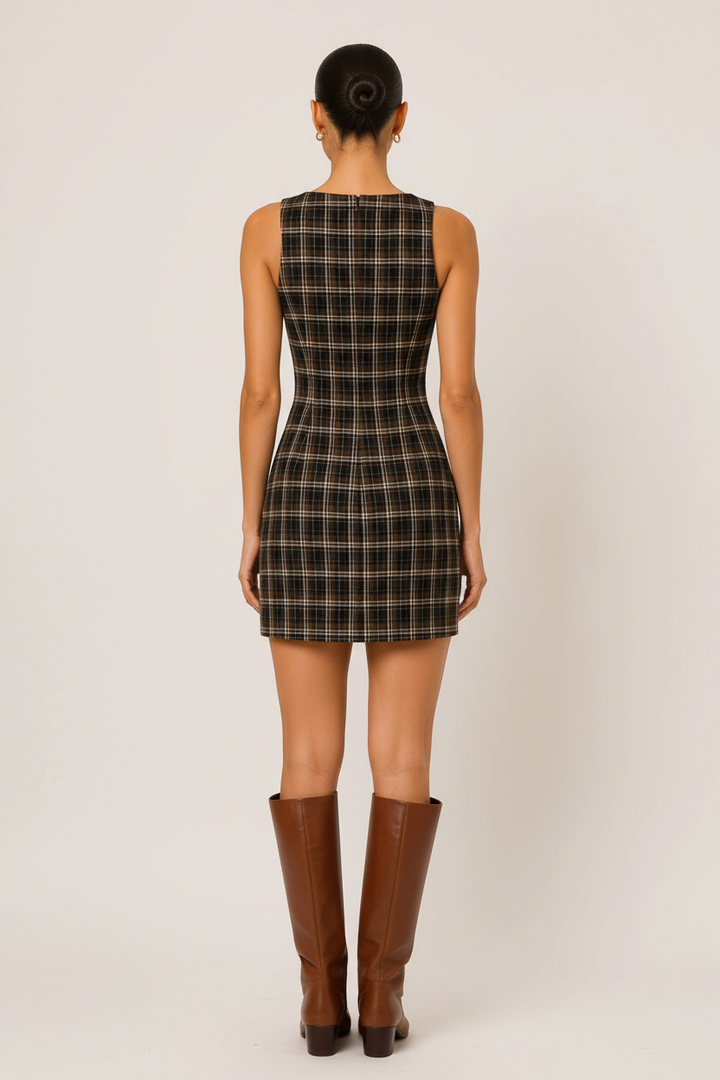 Back view of a model wearing a CAL JUNE sleeveless brown plaid mini dress paired with brown knee-high leather boots.