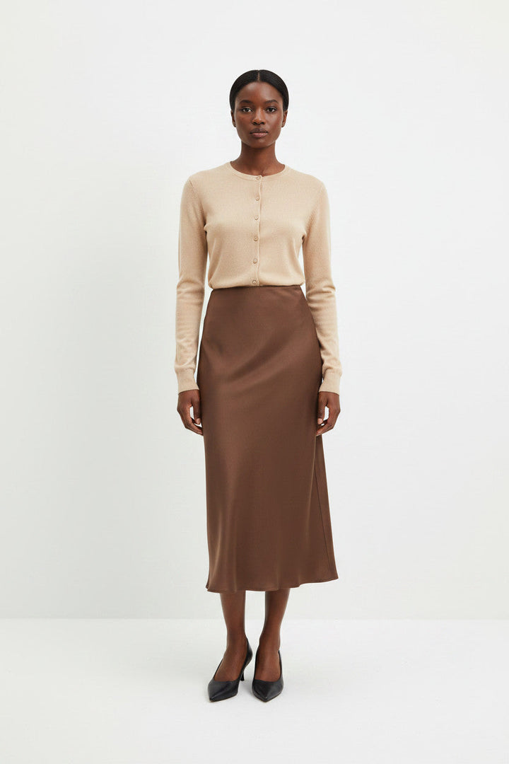 CAL JUNE Seraphina beige ribbed knit button-up cardigan worn with a brown satin midi skirt by a model