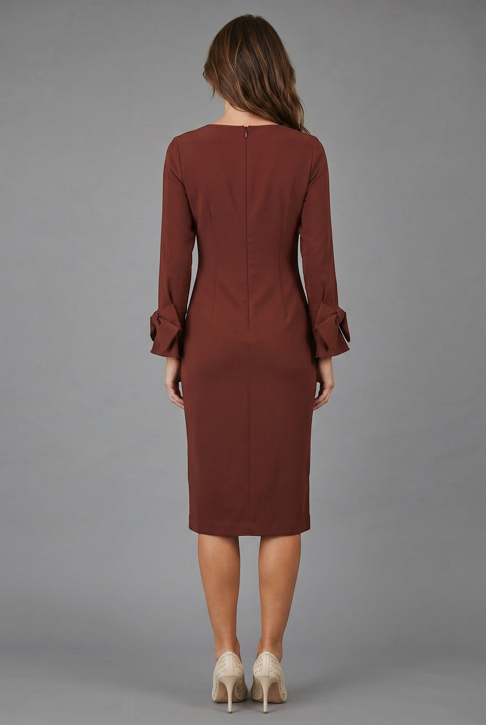 CAL JUNE The Sia Midi Dress in rust brown, featuring long sleeves with bow cuffs and a knee-length pencil skirt. Model wears size S.