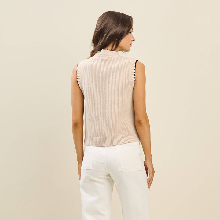 CAL JUNE Sienne sweater vest in beige knit with mock neck and whipstitch trim. Model wears size Small.