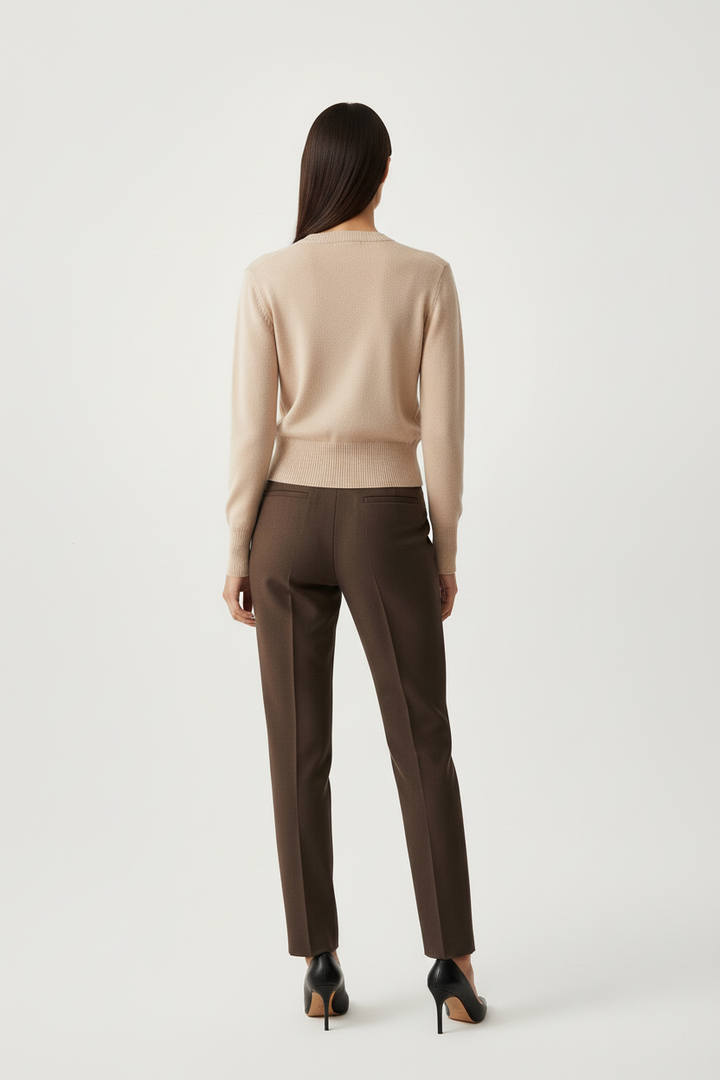 Back view of a model wearing a CAL JUNE tan crewneck cardigan with long sleeves paired with dark brown trousers.