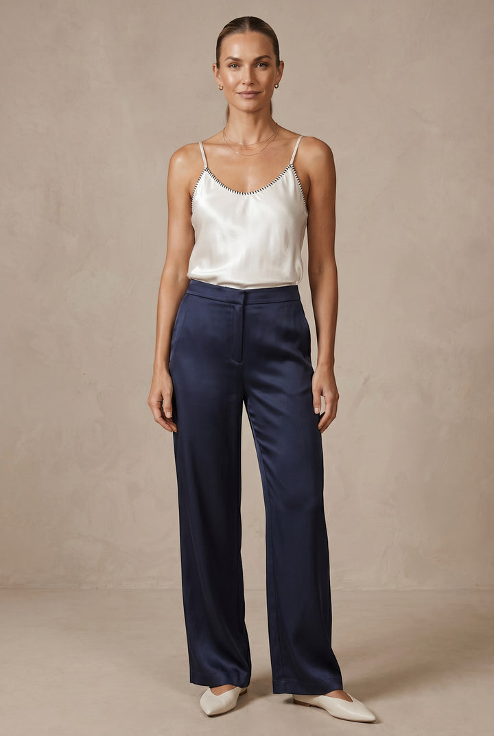 CAL JUNE cream lustrous camisole top with black whipstitch detail on neckline and straps, worn by a model.