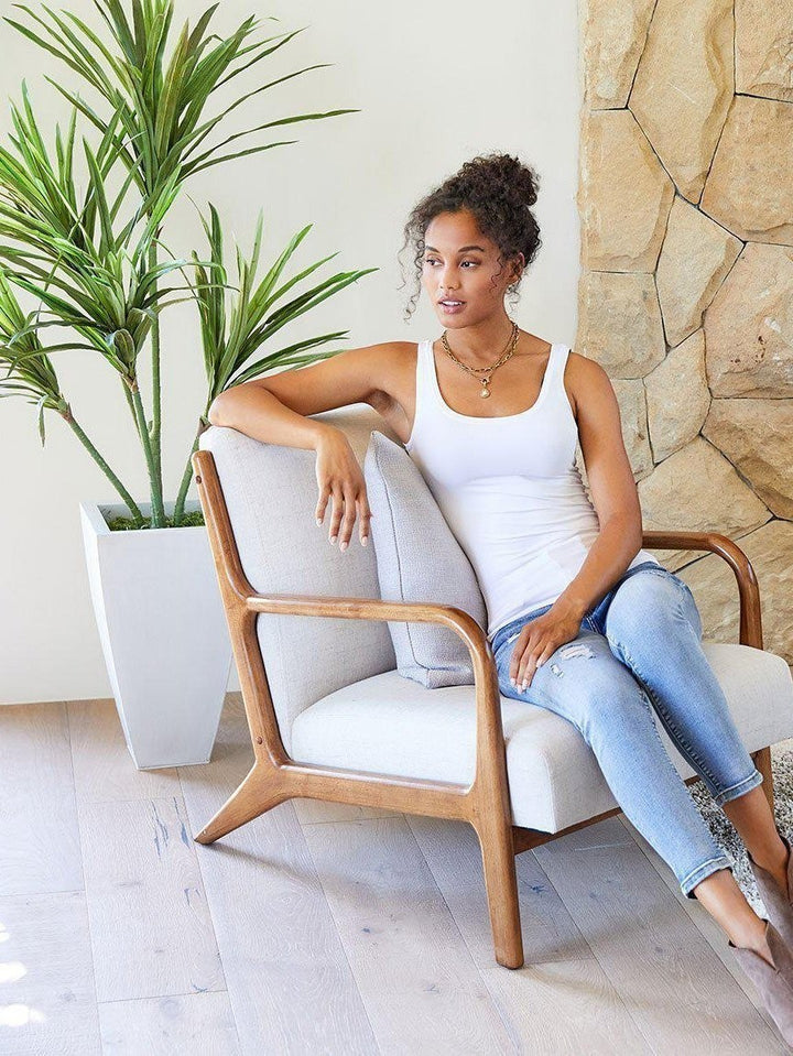 CAL JUNE white ribbed tank top worn by a woman sitting in a chair, styled with jeans and a necklace.